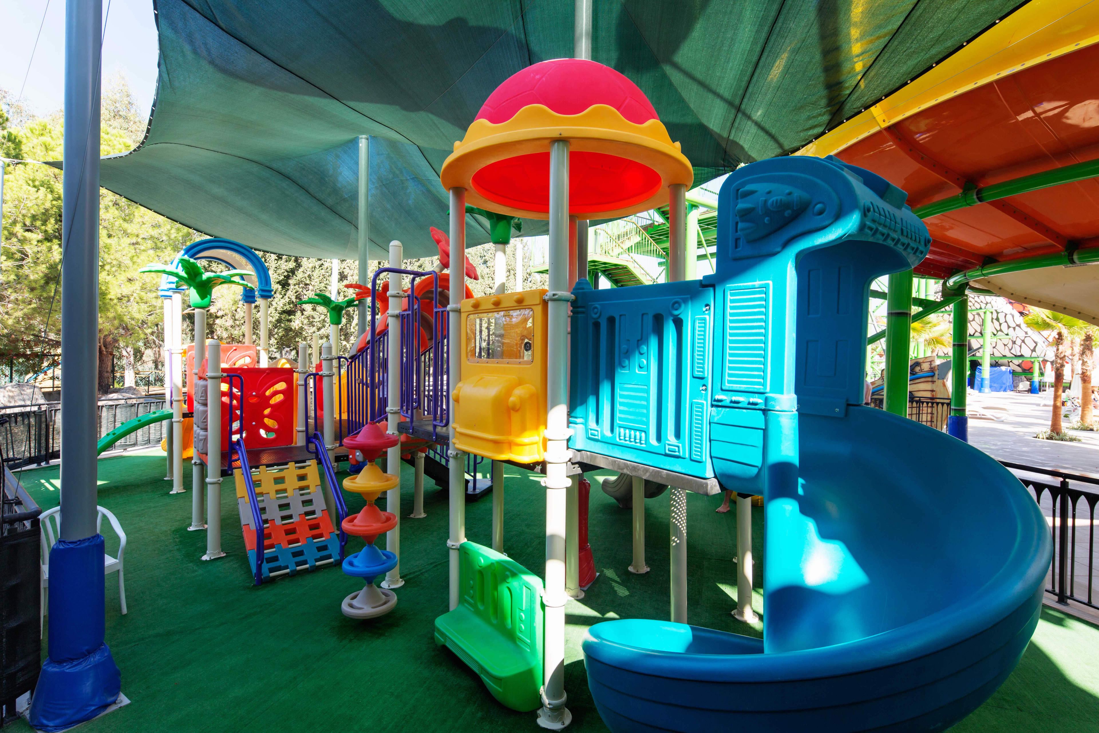 Zona de juegos infantiles con diversas estructuras coloridas y un tobogán.