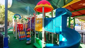 Zona de juegos infantiles con diversas estructuras coloridas y un tobogán.