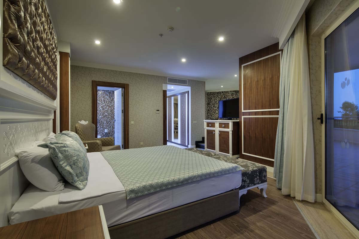 A bedroom with a bed, a TV, a wardrobe, and a bathroom visible through an open door.