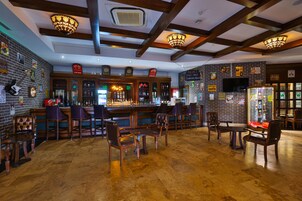 A bar area with wooden furniture, a brick wall, and a television screen.