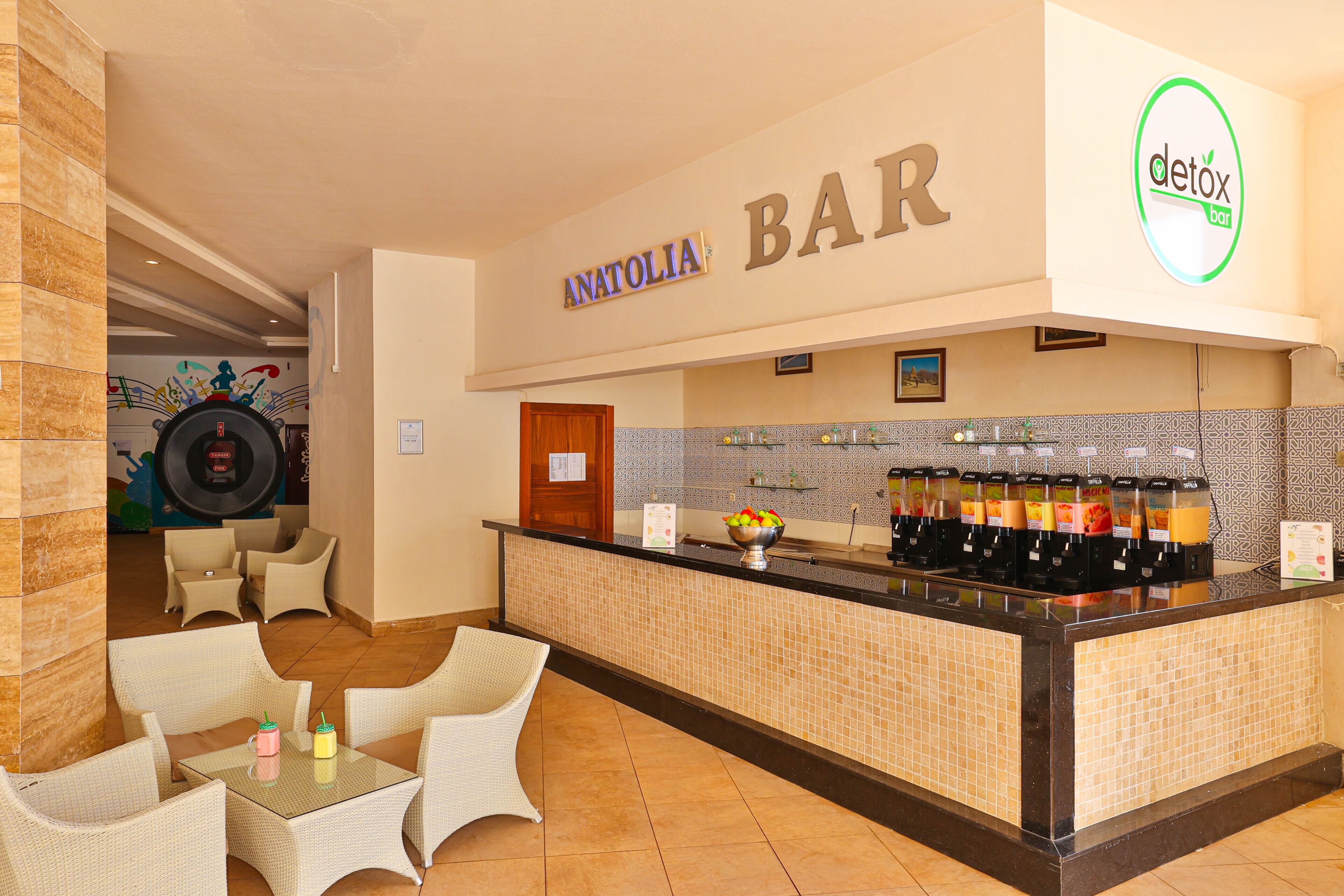 A bar area with a counter, seating, and a wall with a sign reading "ANATOLIA BAR".