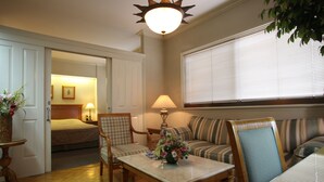 A cozy room with a bed, a sofa, a table with a vase of flowers, and a lamp. - Sunny Bay Suites (Manila)