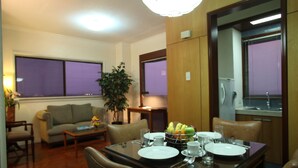 A dining area with a table set for four, a sofa, a coffee table, and a potted plant. - Sunny Bay Suites (Manila)