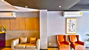 A modern lobby with a sofa and two armchairs, air conditioning units, and a framed artwork on the wall. - H2 Hotel (Bangkok)