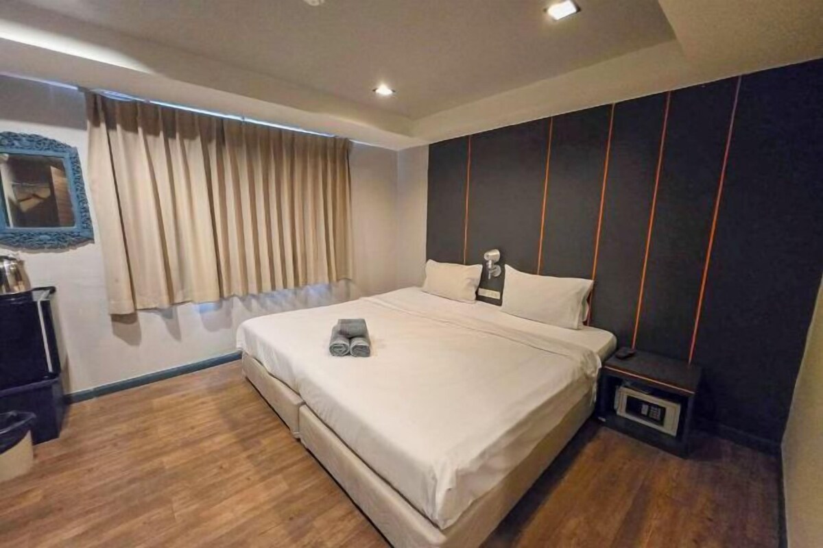 A bedroom with a bed, curtains, a nightstand, and a wall-mounted shelf.