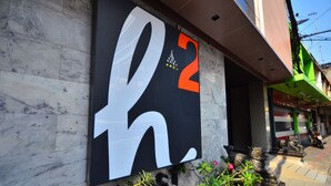 A building facade with a large sign featuring the letters "h2" and "h2ST". - H2 Hotel (Bangkok)