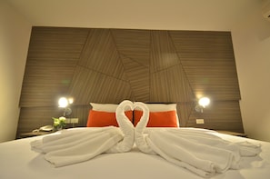 A hotel room with a bed, two bedside lamps, a nightstand with a phone, and a decorative wall panel. - H2 Hotel (Bangkok)