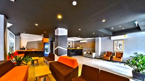 A modern lobby with seating areas, a reception desk, and a kitchen in the background. - H2 Hotel (Bangkok)