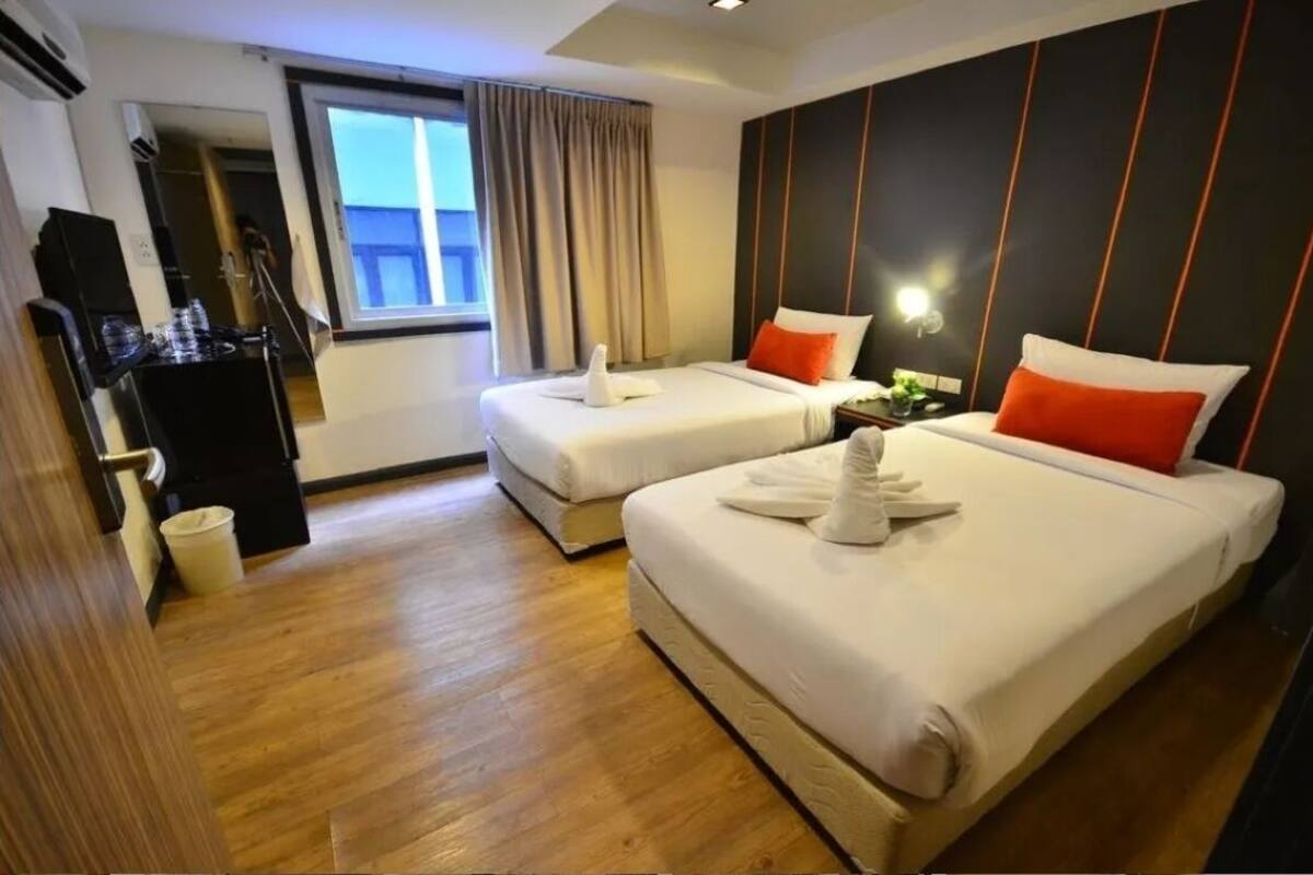 A hotel room with two beds, a desk, and a mirror.