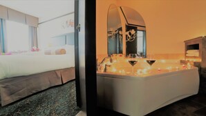 Una habitación de hotel con cama, baño con bañera y espejo.