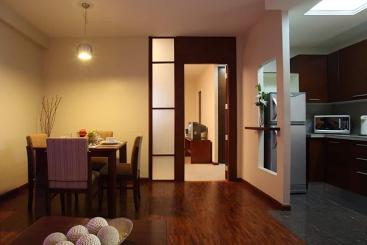 A modern kitchen with dark wood cabinets, a microwave, and a refrigerator.