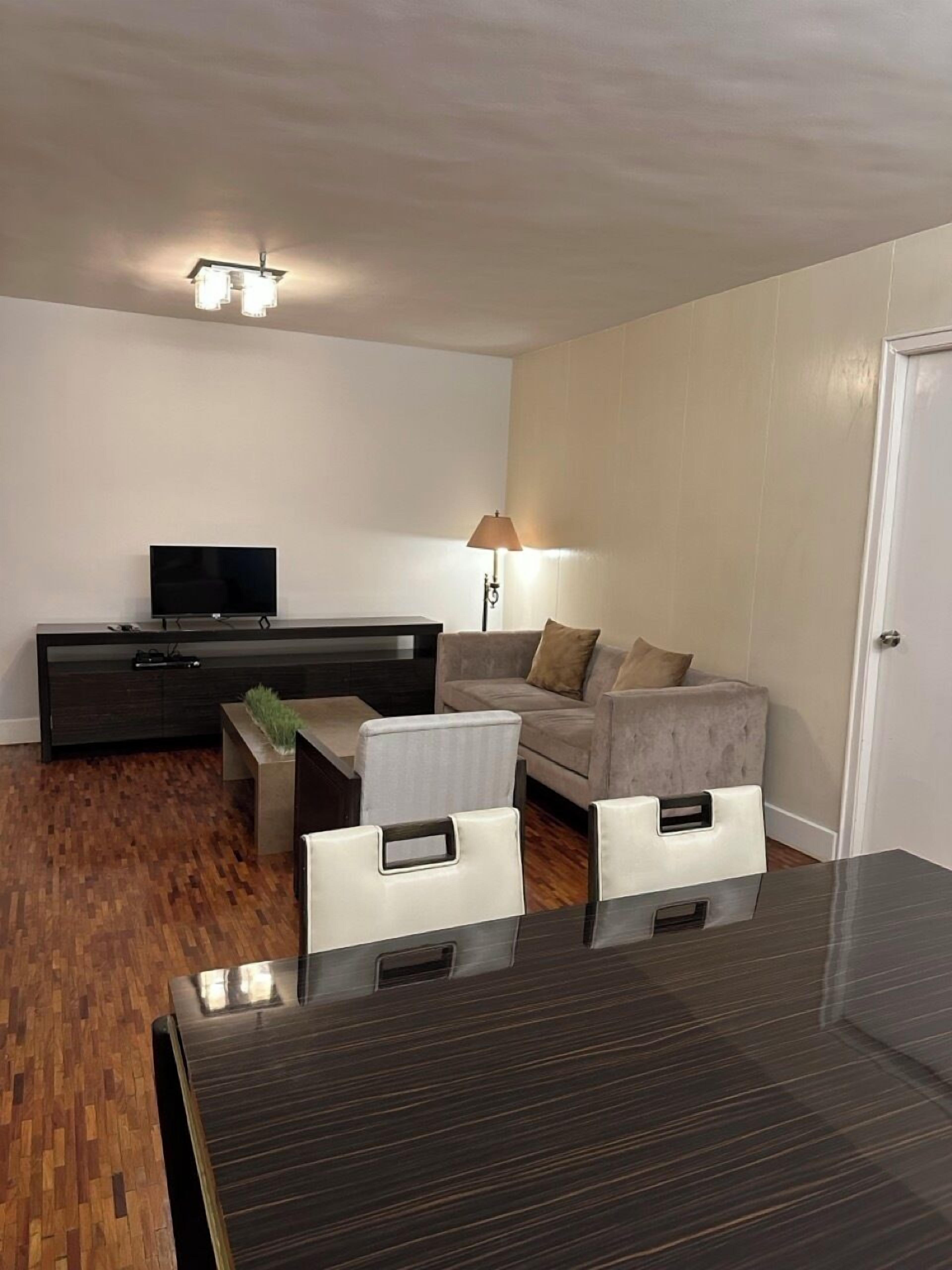 Un salon moderne avec un téléviseur à écran plat, un canapé, une table basse et une lampe.