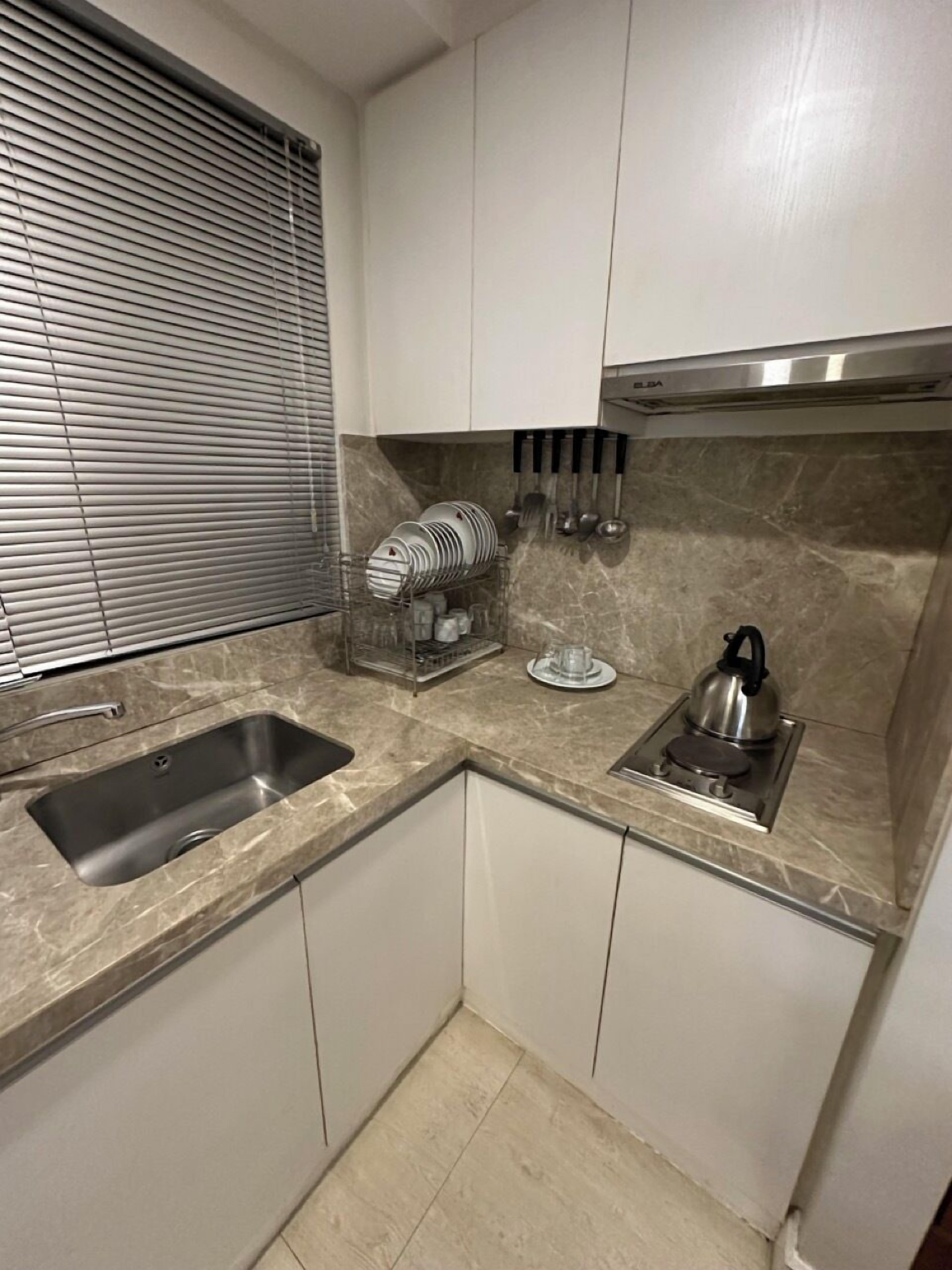 A compact kitchen with a sink, stove, and a dish rack.