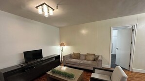 Una sala de estar moderna con una televisión de pantalla plana, un sofá, una mesa de centro y una lámpara.