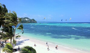 Di pantai, pasir putih, kursi berjemur, dan payung pantai