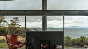 Un salon moderne avec une cheminée, un fauteuil en cuir et une vue sur la mer.