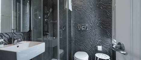 Ein modernes Badezimmer mit einer Duschkabine aus Glas, einem weißen Waschbecken und einer Toilette.