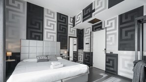 Een moderne hotelkamer met een groot bed, een hoofdbord, een nachtkastje en een kledingkast.