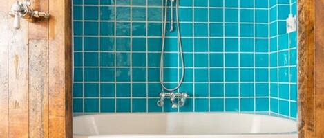A bathroom with a wooden door and a bathtub with blue tiles.