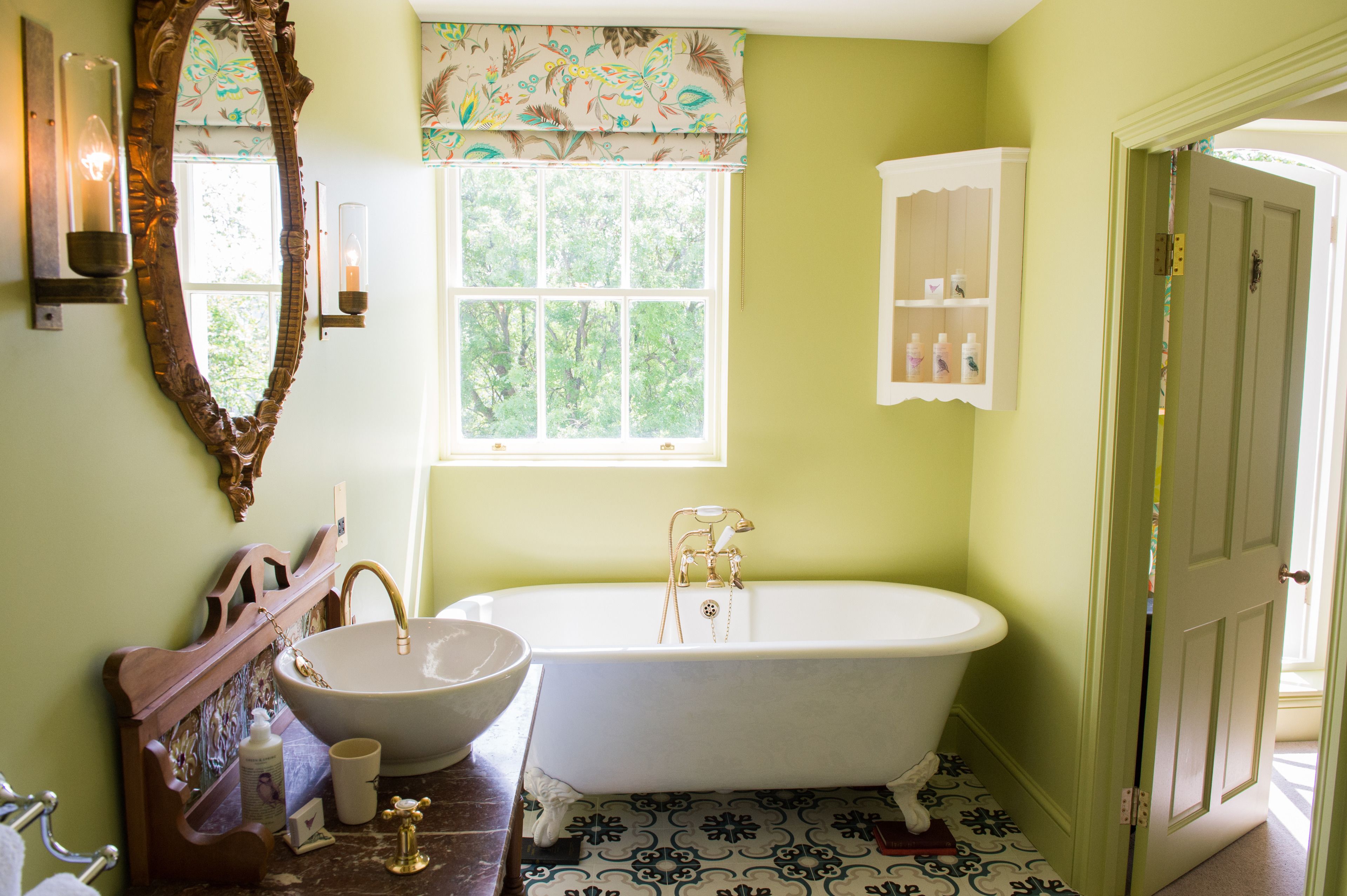 Une salle de bain avec une baignoire sur pieds, un grand miroir, un lavabo et une fenêtre.