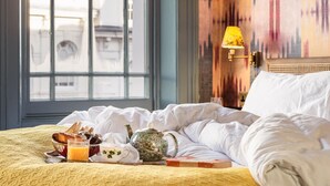 Une chambre d’hôtel avec un lit, un coin pour prendre le petit-déjeuner et une vue sur les bâtiments par la fenêtre.