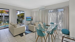 Una sala de estar moderna con una mesa de comedor de vidrio, dos sofás y un televisor.