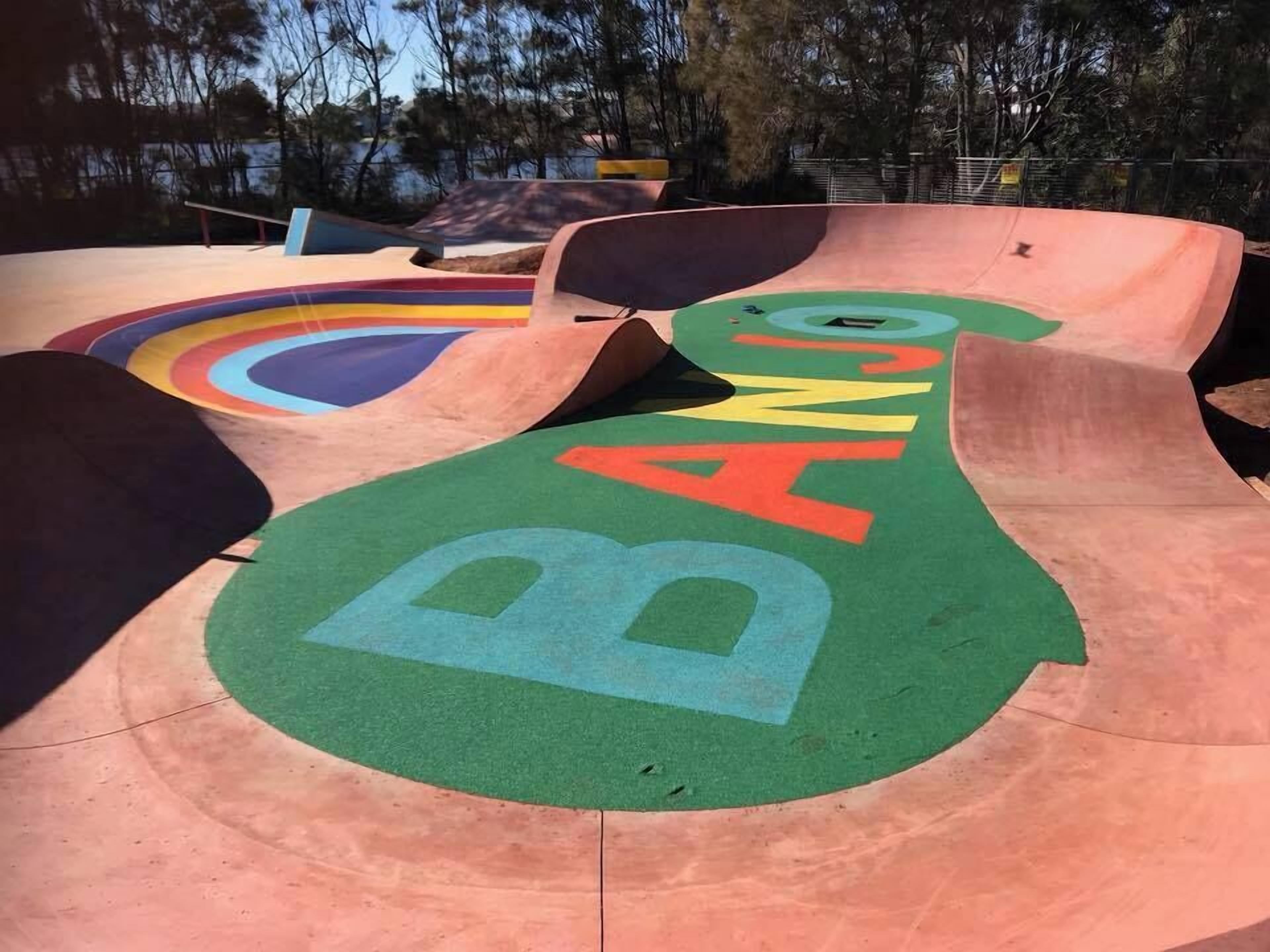 Una pista de skate con rampas y un área verde con la palabra 'BANG' pintada.