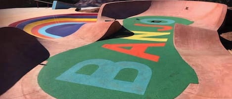 A skate park with ramps and a green area with the word 'BANG' painted on it.