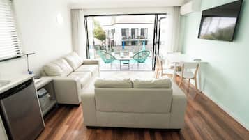 A modern living room with a sofa, dining table, chairs, and a TV.