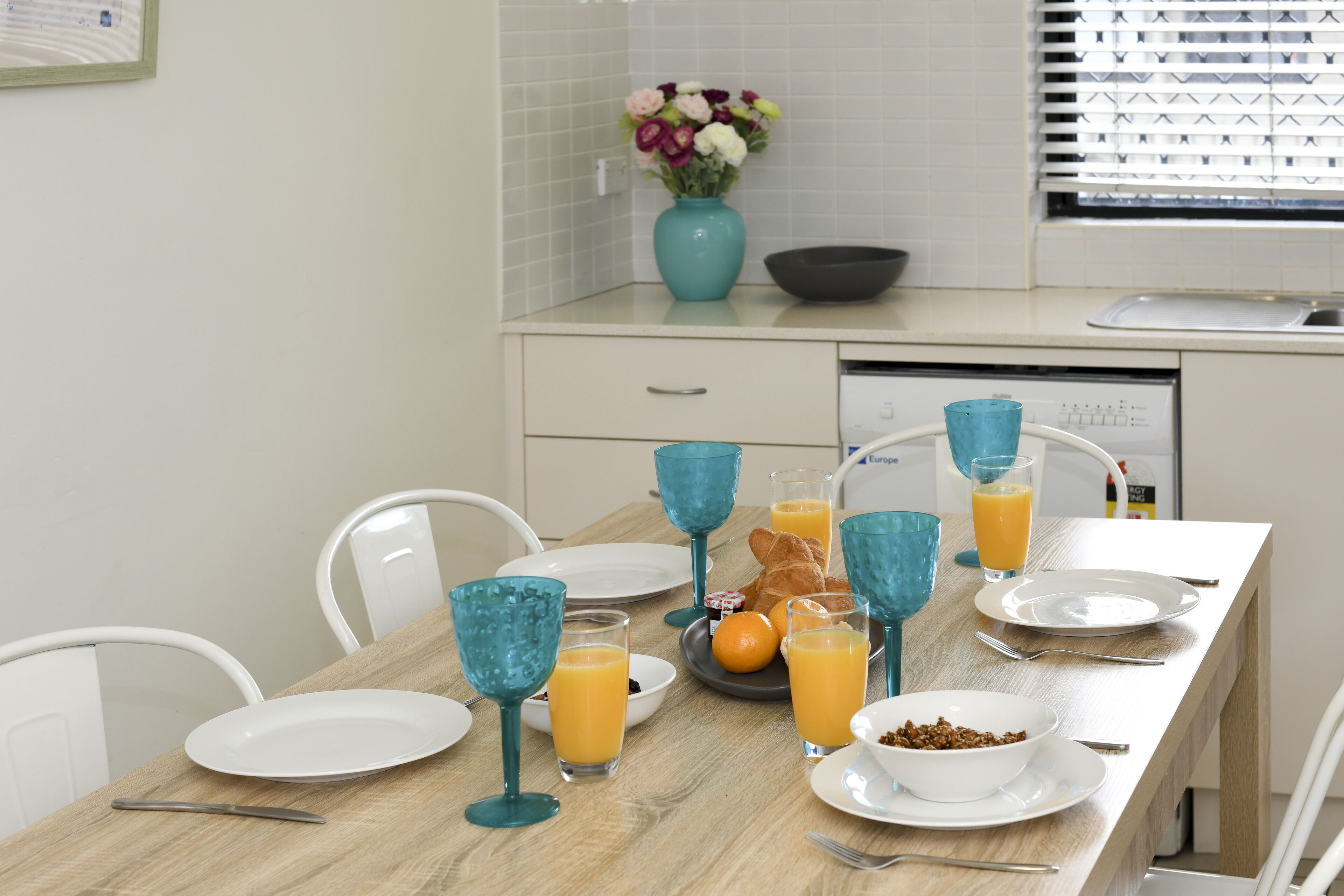 Una mesa de desayuno dispuesta con platos, vasos y un bol de cereal.