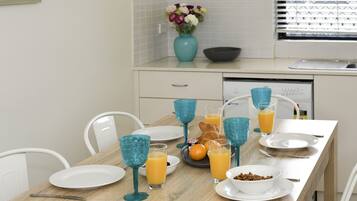 Una mesa de desayuno dispuesta con platos, vasos y un bol de cereal.