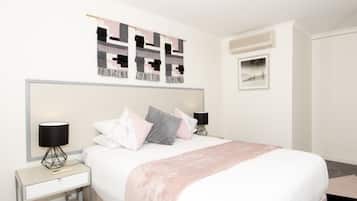 A modern bedroom with a large bed, bedside tables, and a wall-mounted artwork.