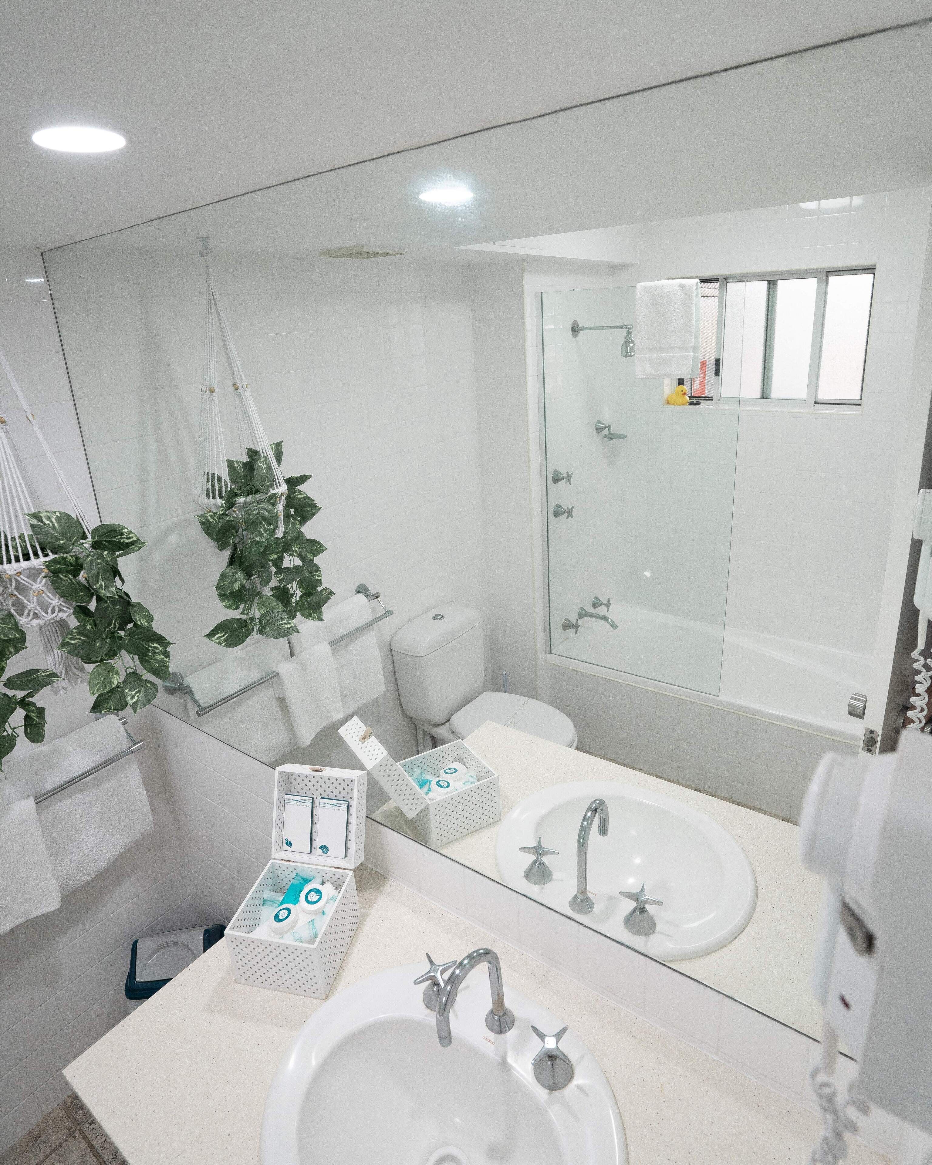 A modern bathroom with a glass shower enclosure, white fixtures, and a large mirror.