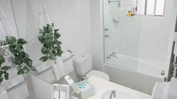 A modern bathroom with a glass shower enclosure, white fixtures, and a large mirror.