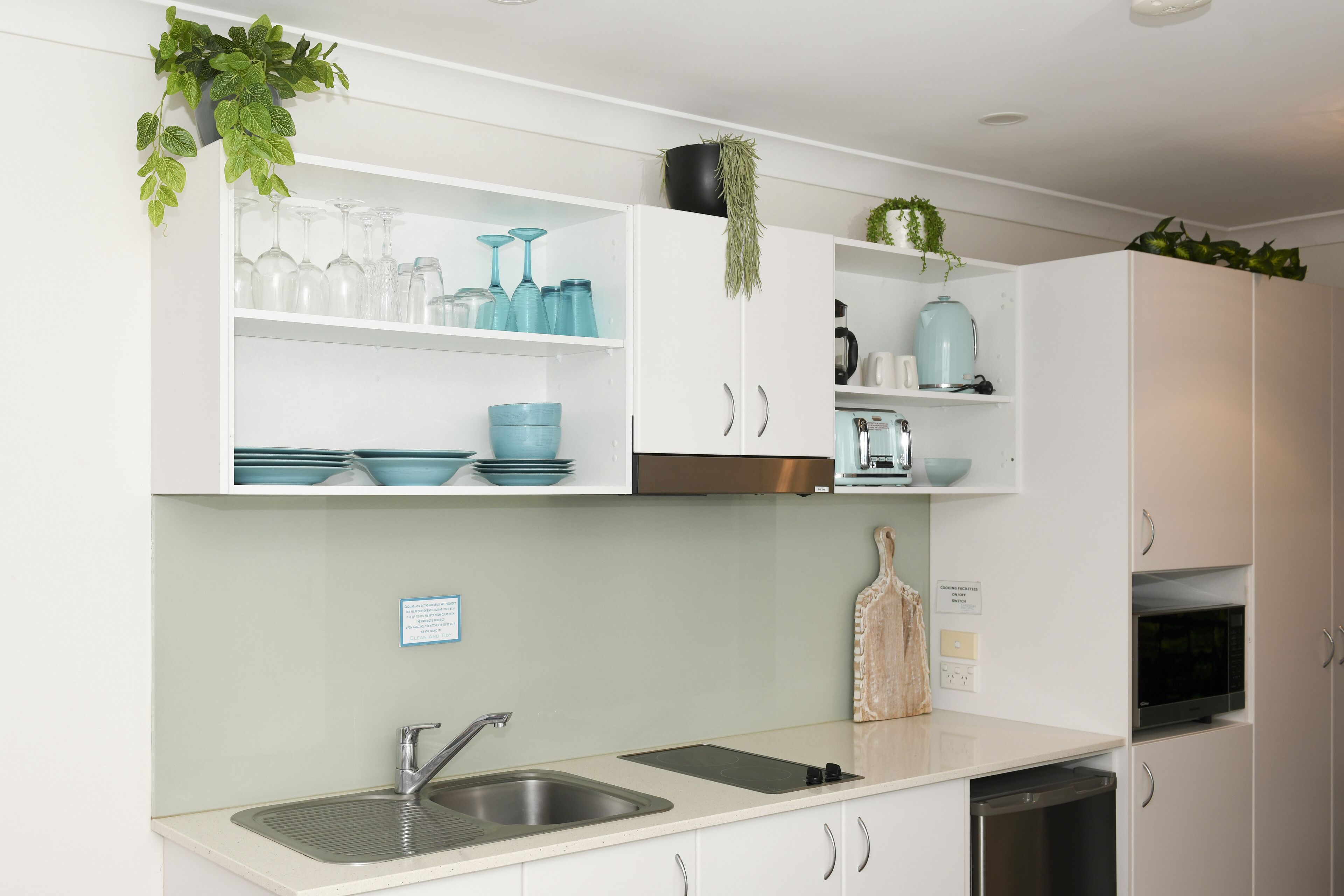 Una cucina moderna con mobili bianchi, un lavello doppio e diversi elettrodomestici.