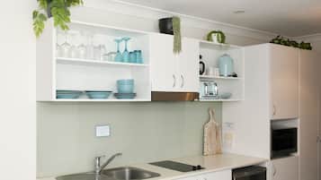 A modern kitchen with white cabinets, a double sink, and various kitchen appliances.