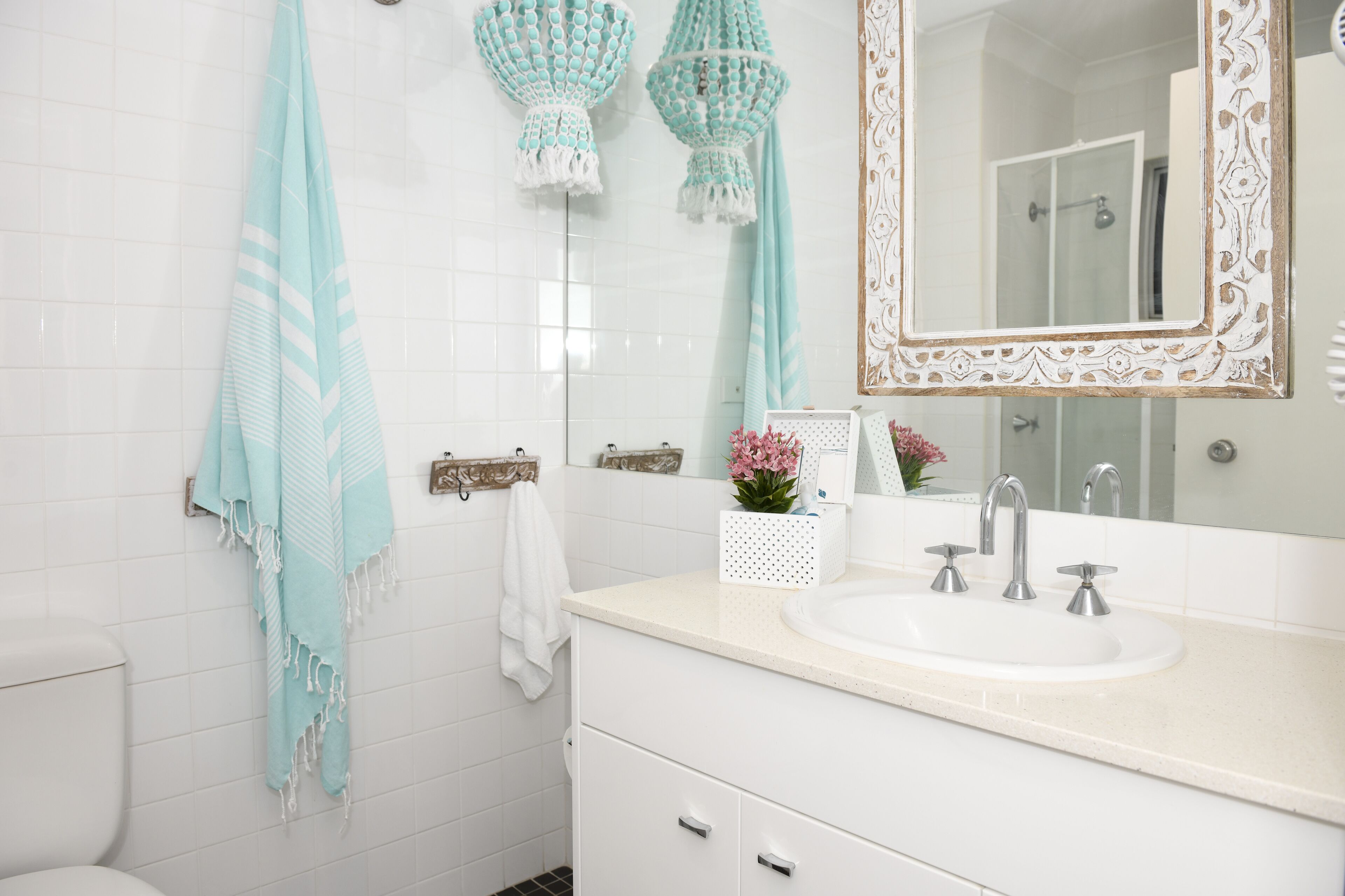 A bathroom with a white sink, a mirror with an ornate frame, and a towel hanging on the wall.