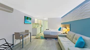 Ein modernes Hotelzimmer mit Bett, einer Couch, einem Schreibtisch und einer Küchenzeile.