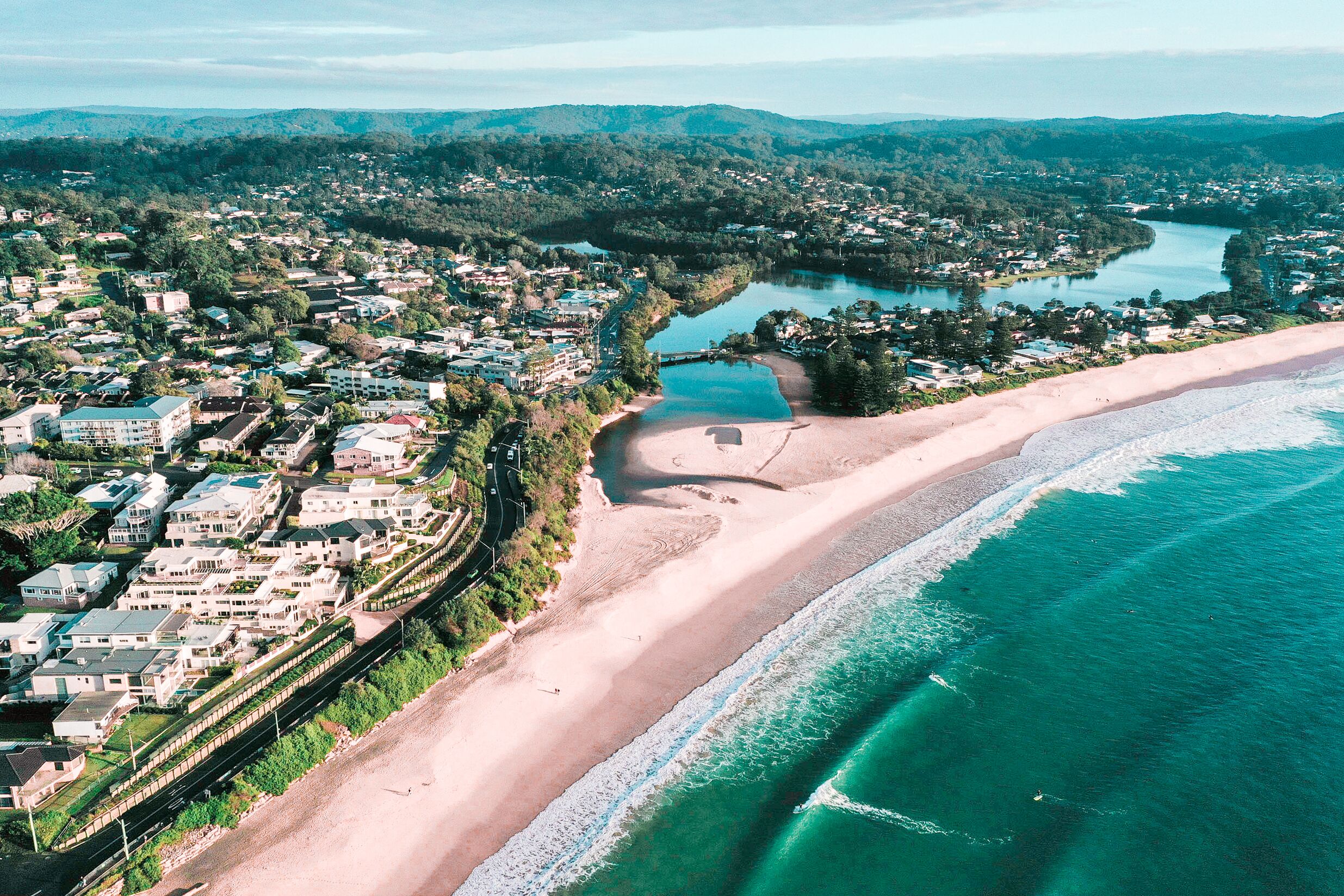 Vista aérea de un pueblo costero con playa, edificios residenciales y un río.