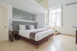 Un dormitorio moderno con una cama grande, una mesita de noche, una pequeña mesa con un teléfono, una ventana con vistas y una escalera.