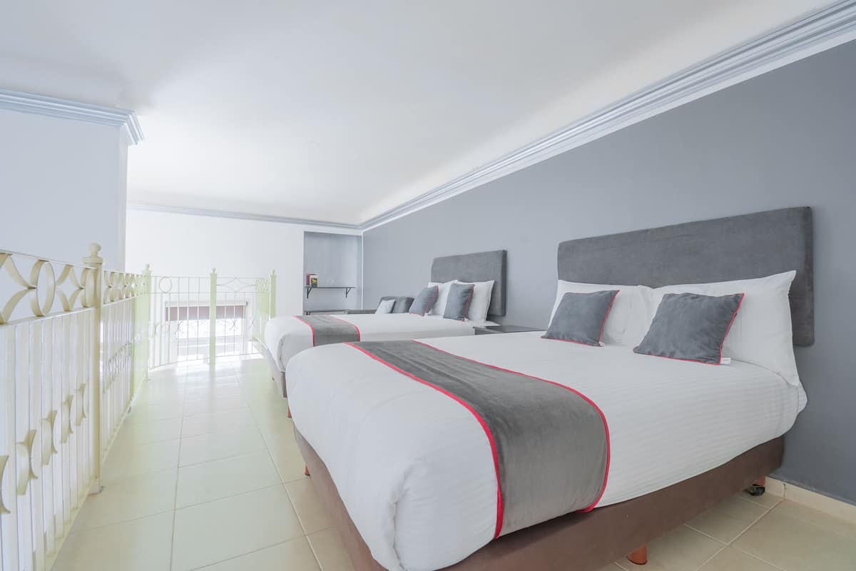 A hotel room with two beds, a balcony, and a view of the sea.