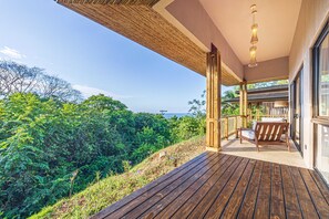 Una terraza de madera con vistas a una vegetación densa y el océano.