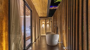 A corridor with a wooden floor, a large white bathtub, and a glass door leading to a bathroom. - Tiki Villas Rainforest Lodge & Spa (Bahía Ballena)