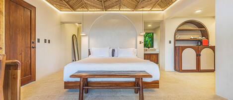 A bedroom with a bed, wooden bench, ceiling fan, and a wooden cabinet.