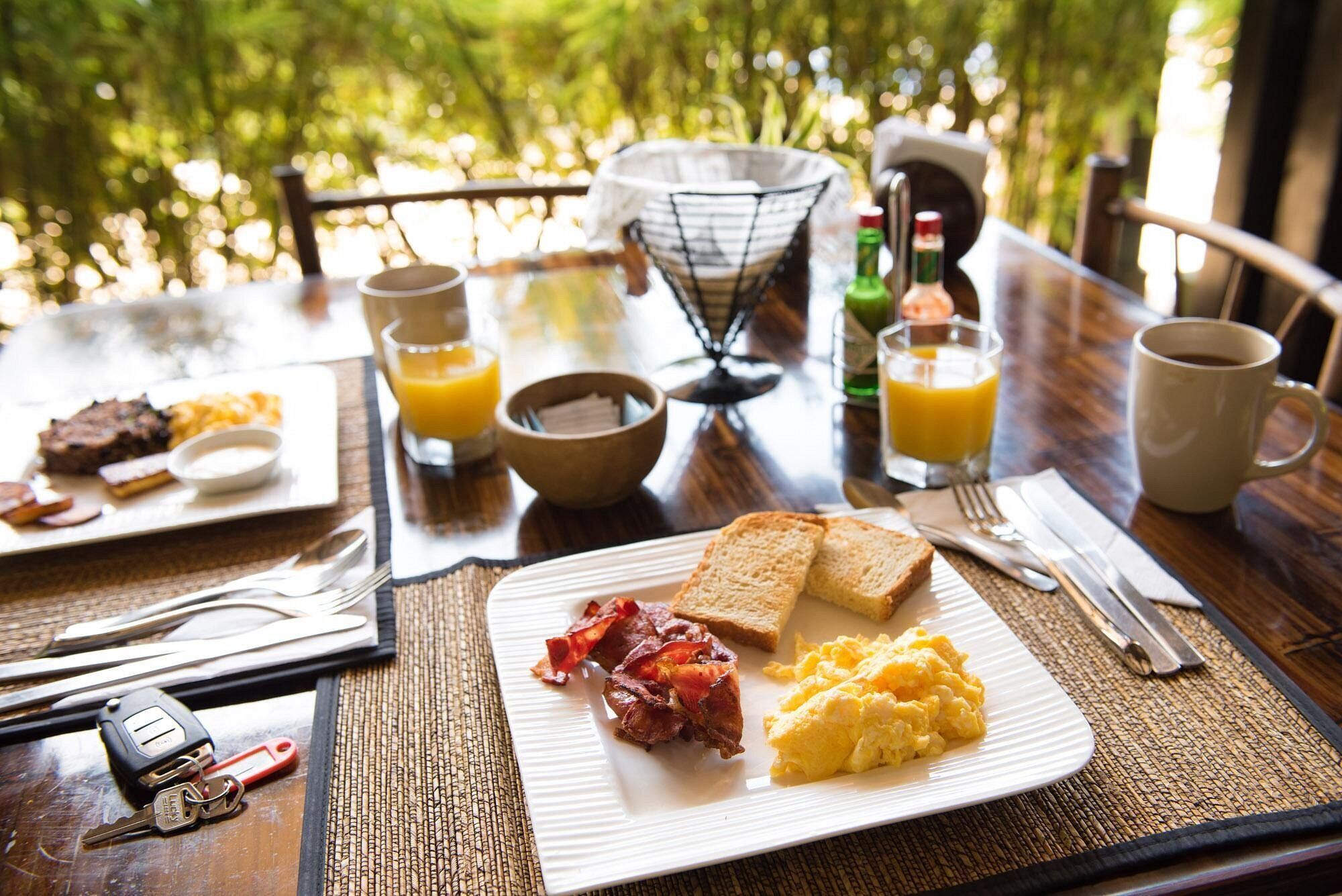 Desayuno con tostadas, huevos revueltos, tocino y jugo.