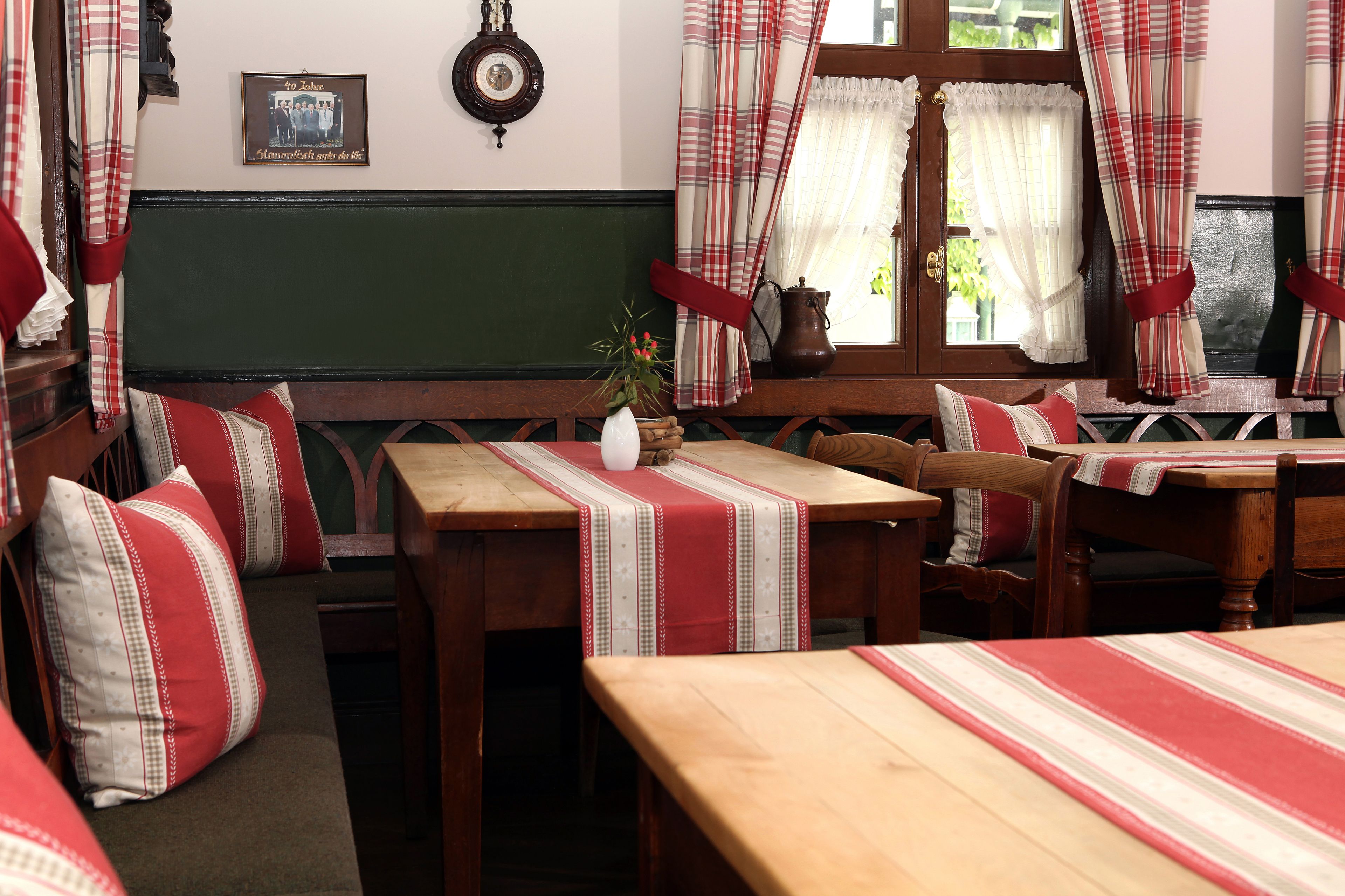 A traditional inn room with wooden furniture, plaid curtains, and a green wall.