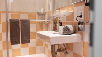 A bathroom with a white sink, a glass shower enclosure, and two towels hanging on a rack.