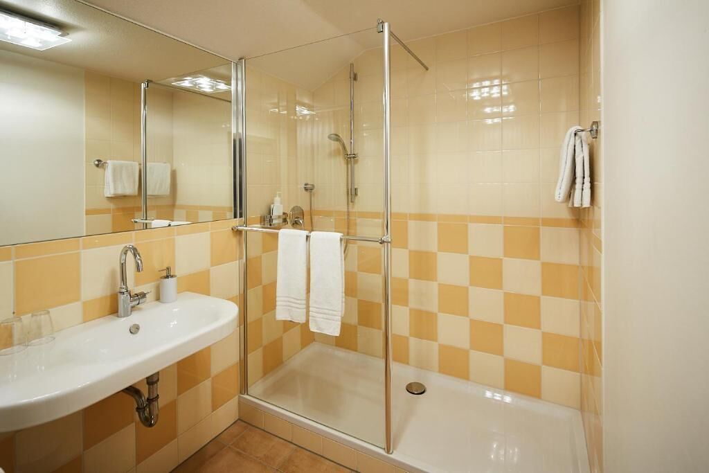 A bathroom with a glass-enclosed shower, a sink, and a mirror.