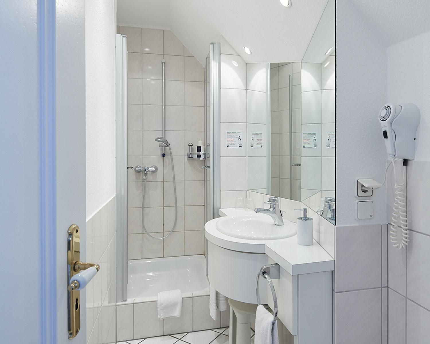 Ein modernes Badezimmer mit einer gläsernen Duschkabine, einer Badewanne und einem Waschtisch mit Spiegel.