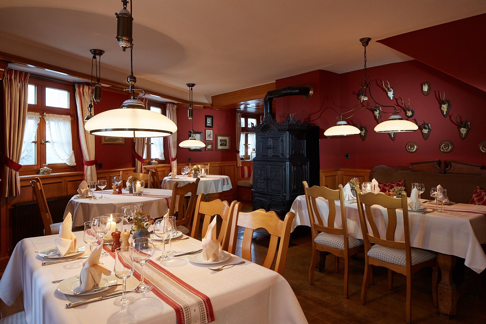 A restaurant with multiple tables set for dining, wooden chairs, and a vintage-style wall decor.